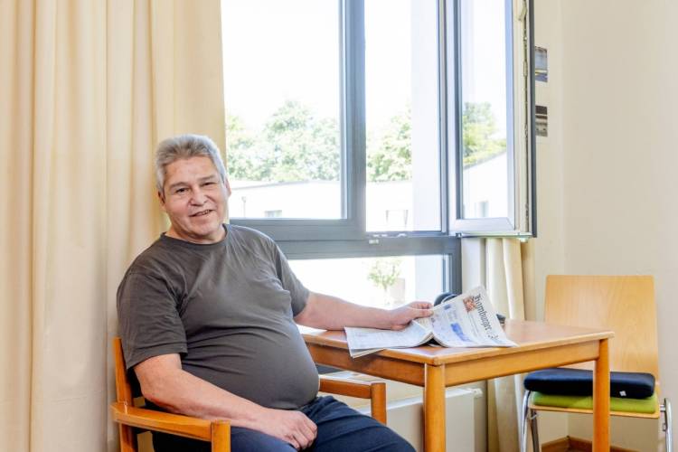 Victor Vargas am Tisch mit einer Zeitung bei PFLEGEN & WOHNEN HAMBURG am Standort Öjendorf.