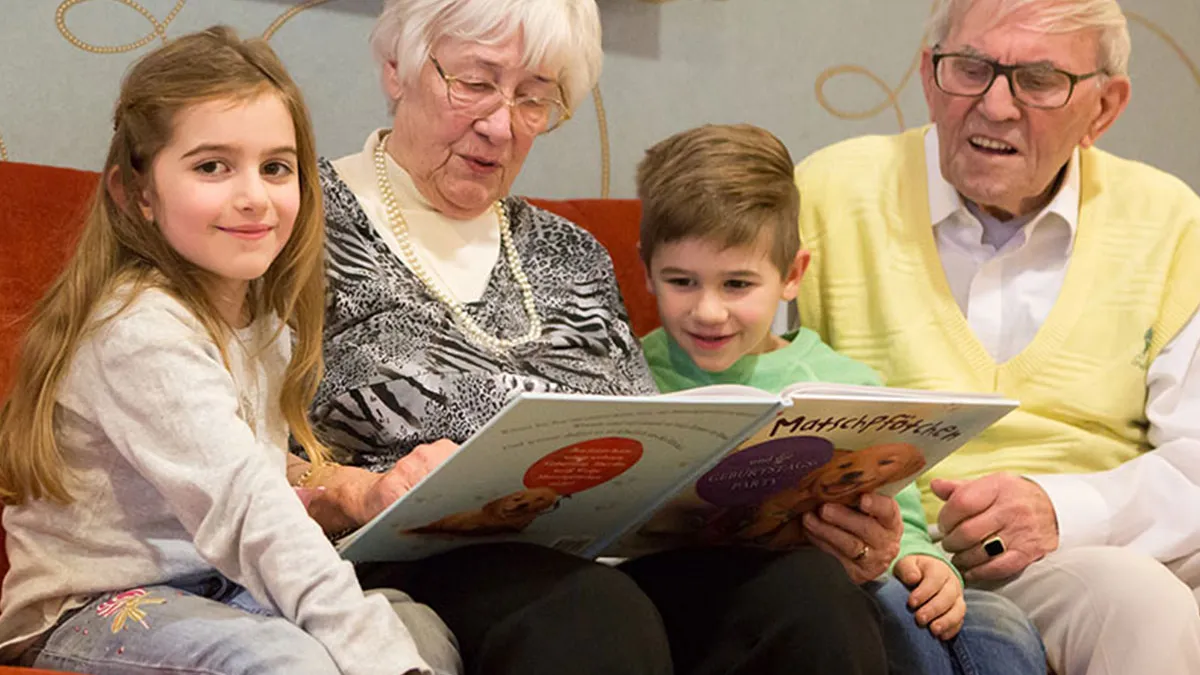 Ehepaar, das im PFLEGEN & WOHNEN HAMBURG Finkenau lebt, liest seinen Enkelkindern vor.