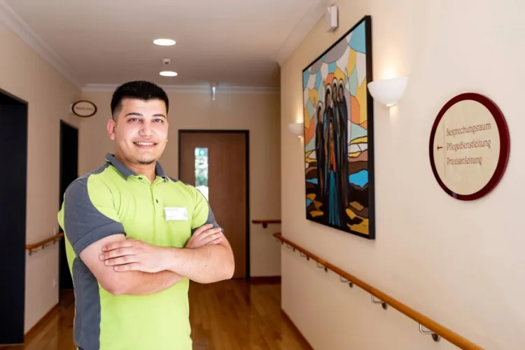 Jaid Shani Baqi, Mitarbeiter bei PFLEGEN & WOHNEN HAMBURG, auf dem Flur des Standorts Finkenau, schätzt Respekt, Empathie und Fachkompetenz in der Pflege.