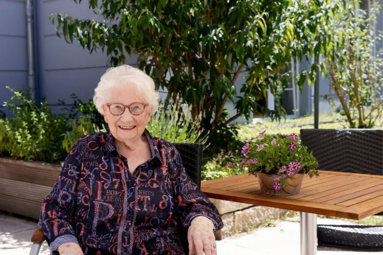 Ursula Heiden im Außenbereich des Standorts Holstenhof bei PFLEGEN & WOHNEN HAMBURG, schätzt vielfältige Aktivitäten in der Pflege.
