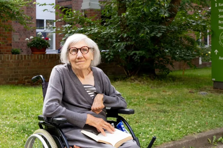 Margit Leinweber mit einem Buch vor PFLEGEN & WOHNEN HAMBURG am Standort Altona.