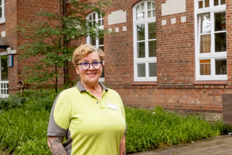 Malgorzata Bochenska vor dem Außenbereich bei PFLEGEN & WOHNEN HAMBURG am Standort Farmsen.