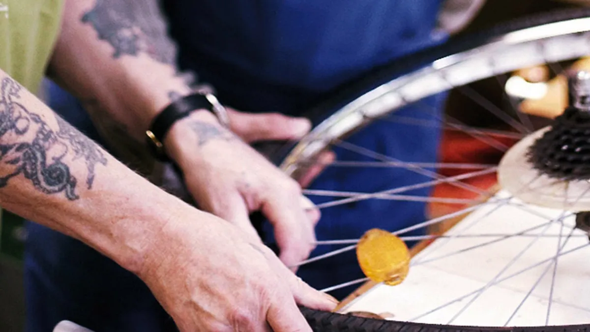 Ein Mitarbeiter repariert ein Rad eines Fahrrads bei PFLEGEN & WOHNEN HAMBURG in Öjendorf.