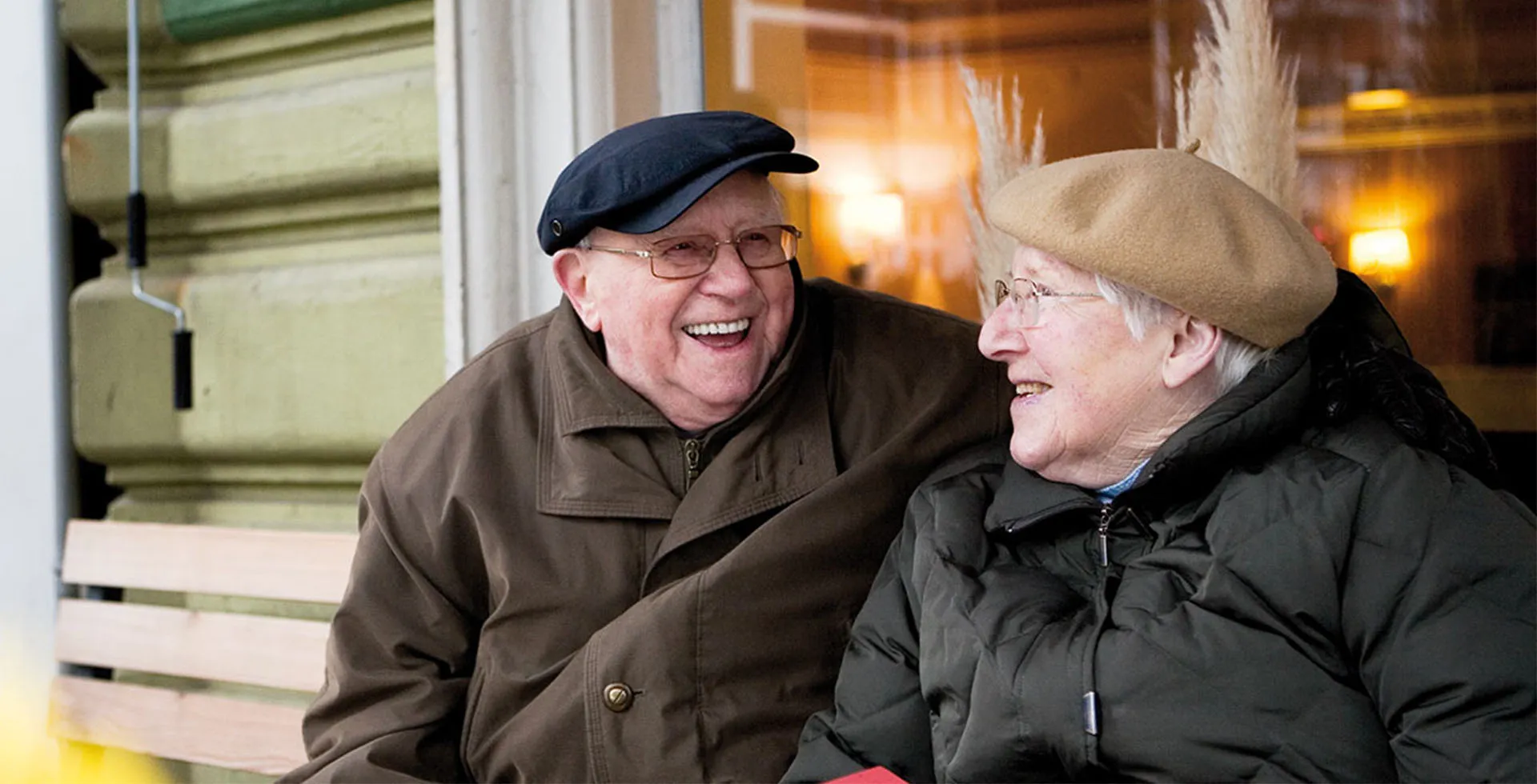 In Altona sitzt ein Rentnerpaar auf einer Bank und freut sich über die liebevolle Betreuung durch PFLEGEN & WOHNEN HAMBURG.