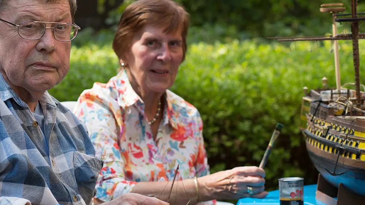 Ehepaar, das im PFLEGEN & WOHNEN HAMBURG am Standort Lutherpark lebt, bemalt in der Freizeit ein Schiffmodell.