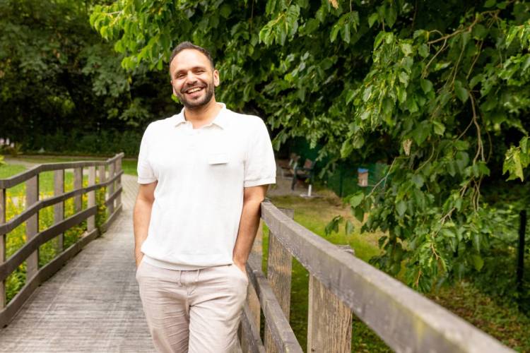 Wasim Najjar auf einer Brücke im grünen Außenbereich des Standorts Wilhelmsburg bei PFLEGEN & WOHNEN HAMBURG.