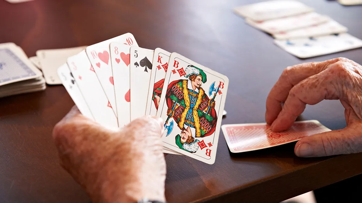 Nahaufnahme der Hände eines Bewohners von PFLEGEN & WOHNEN HAMBURG Holstenhof beim Kartenspiel.