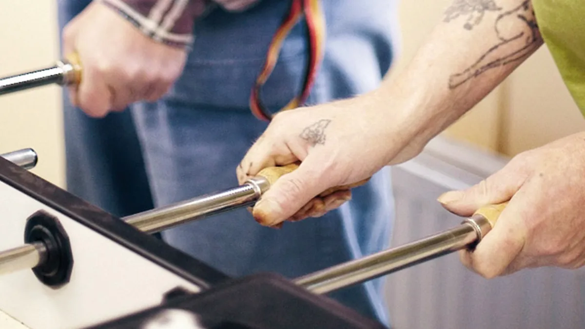 Bewohner und Pflegekräfte beim Tisch Kicker Spielen während der Freizeit bei PFLEGEN & WOHNEN HAMBURG in Öjendorf.