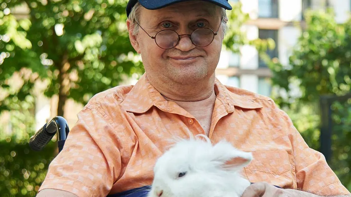 Bewohner von PFLEGEN & WOHNEN HAMBURG Alsterberg mit einem weißen Kaninchen auf dem Schoß.