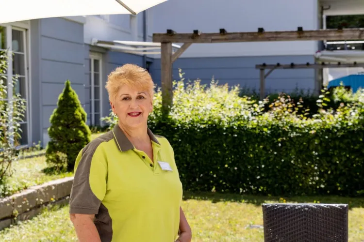 Pflegekraft Dagmar Weick im Außenbereich des Standorts Holstenhof bei PFLEGEN & WOHNEN HAMBURG setzt Bewohnerzufriedenheit an erster Stelle.