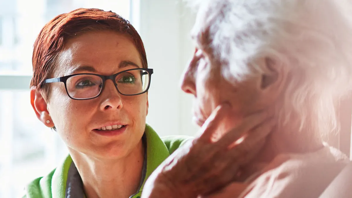 Nahaufnahme einer Pflegerin, die mit einer Bewohnerin im PFLEGEN & WOHNEN HAMBURG Finkenau spricht.