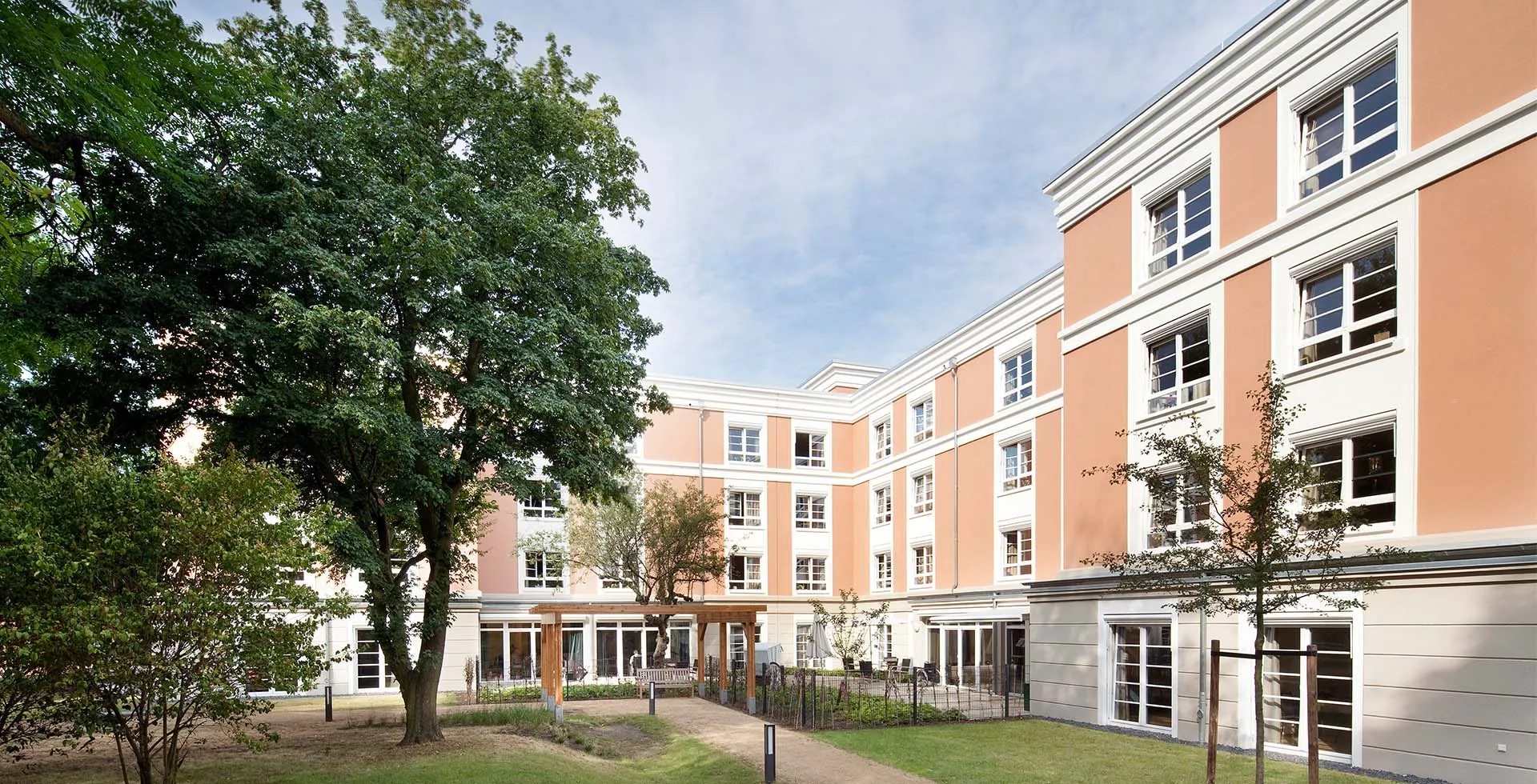 Außenansicht der Einrichtung PFLEGEN & WOHNEN HAMBURG Finkenau mit begrüntem Innenhof und Fokus auf Pflege und Betreuung.