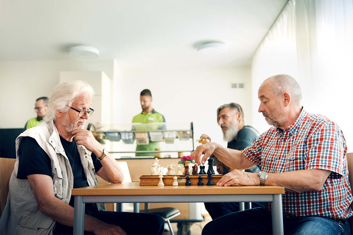 Im modernen Gemeinschaftsraum von PFLEGEN & WOHNEN ÖJENDORF treffen sich Bewohner zum gemeinsamen Schachspiel.