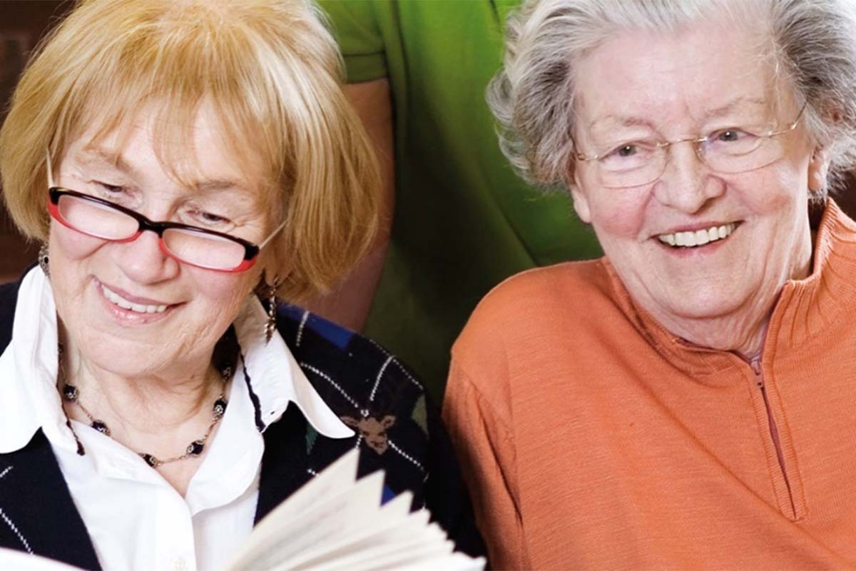 Zwei Bewohnerinnen von PFLEGEN & WOHNEN HAMBURG lesen gemeinsam ein Buch und genießen die gemeinsame Zeit.